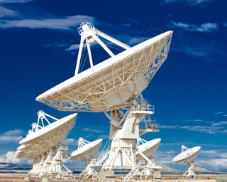 Radio telescope dishes under a blue sky.