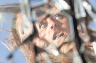 A terrified woman reflected in a broken mirror