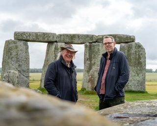Phil Harding and Matt Leivers stand in front of stones at Stonehenge.